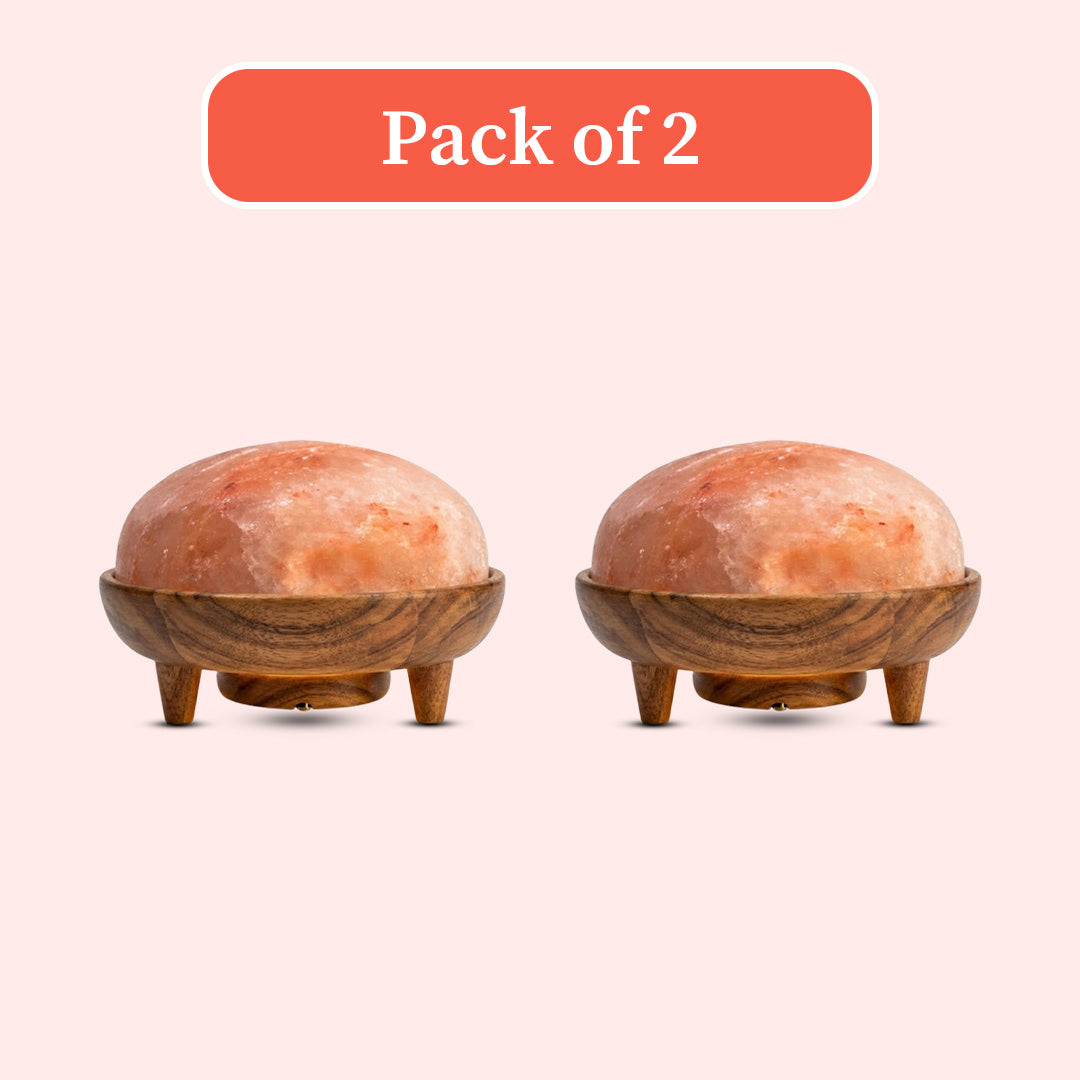Two dome-shaped pink salt lamp shapers with carved wooden bases and small legs, shown side by side on a pale pink background with a coral 'Pack of 2' label above.