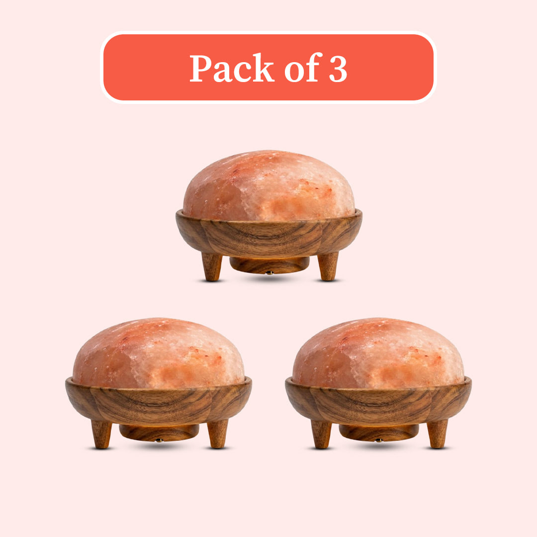 Three dome-shaped pink salt lamps in wooden holders, arranged on a pale pink background with an orange label at the top reading 'Pack of 3'.