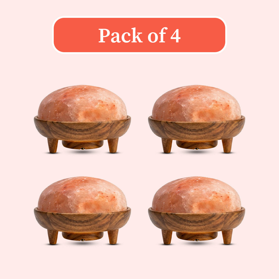 Four identical dome-shaped pink salt lamps with carved wooden bases and legs, arranged in a 2x2 grid on a pale pink background with an orange label reading 'Pack of 4'.