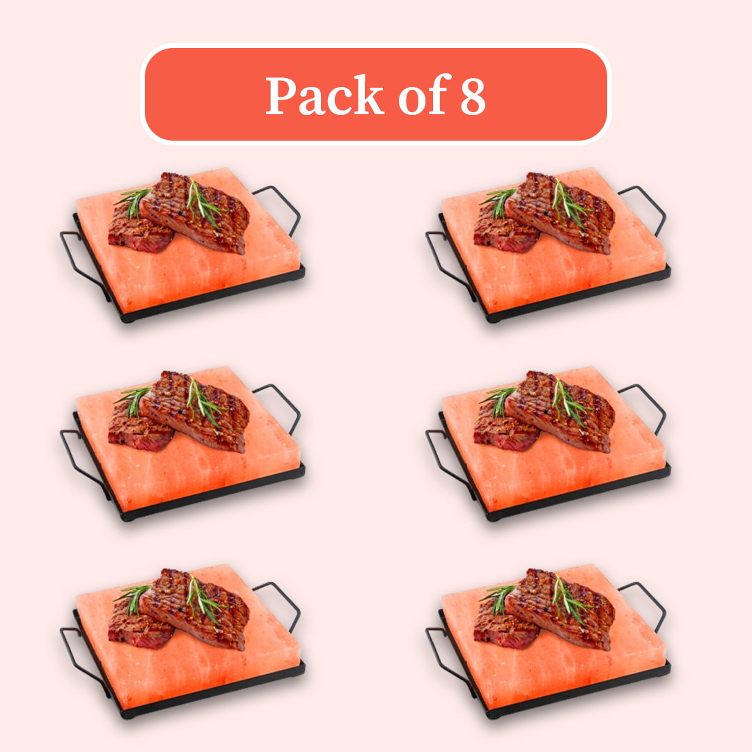 Six identical small rectangular grills with black metal handles sit on bright orange stones, each topped with grilled meat and a green herb sprig. A coral-colored label at the top reads 'Pack of 8' on a pale pink background.